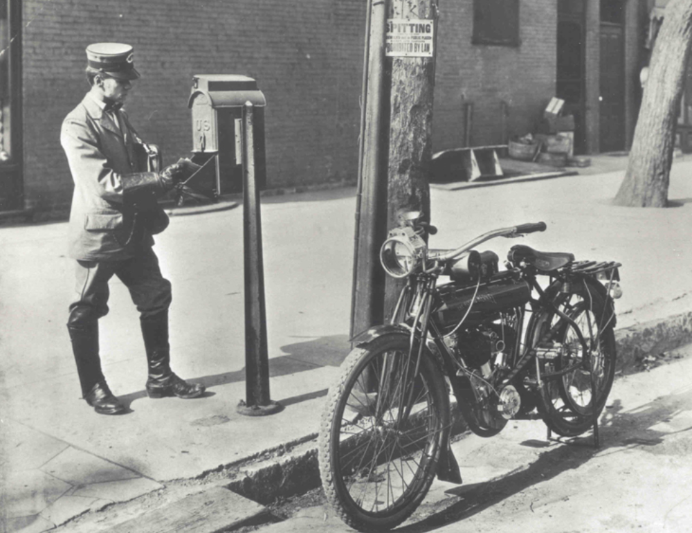 old photograph of a letter carrier with a motorcycle